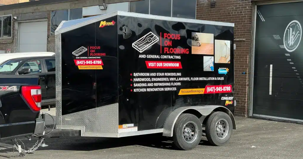 Focus on Flooring Trailer branding project. Photo taken during passenger pickup. Trailer graphics seen from front left side view.