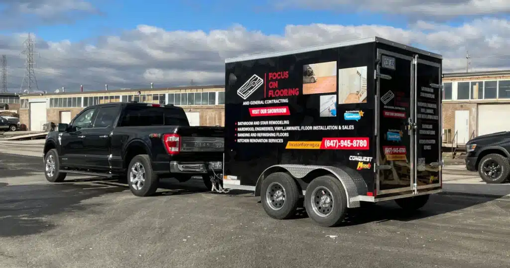 Focus on Flooring trailer branding project. Photo taken during passenger pickup. Trailer graphics seen from back left side view.
