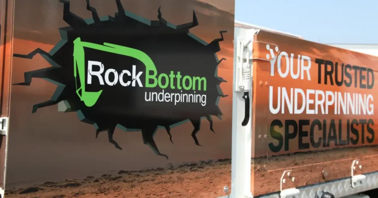 A close-up angled side view of a Freightliner wrap highlighting the Rock Bottom Underpinning company decals