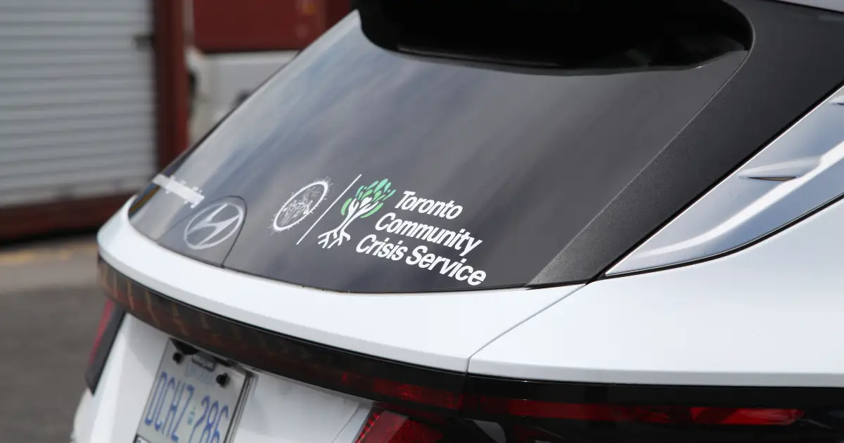 A close-up rear angle shot of a Hyundai Tucson, showcasing decals from the Toronto Community Crisis Services on the company vehicle.