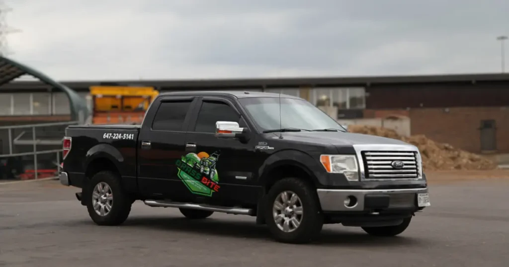 A 2014 Ford F-150 Super Cab truck shown from an angled side view, showcasing Grass Bite company decals