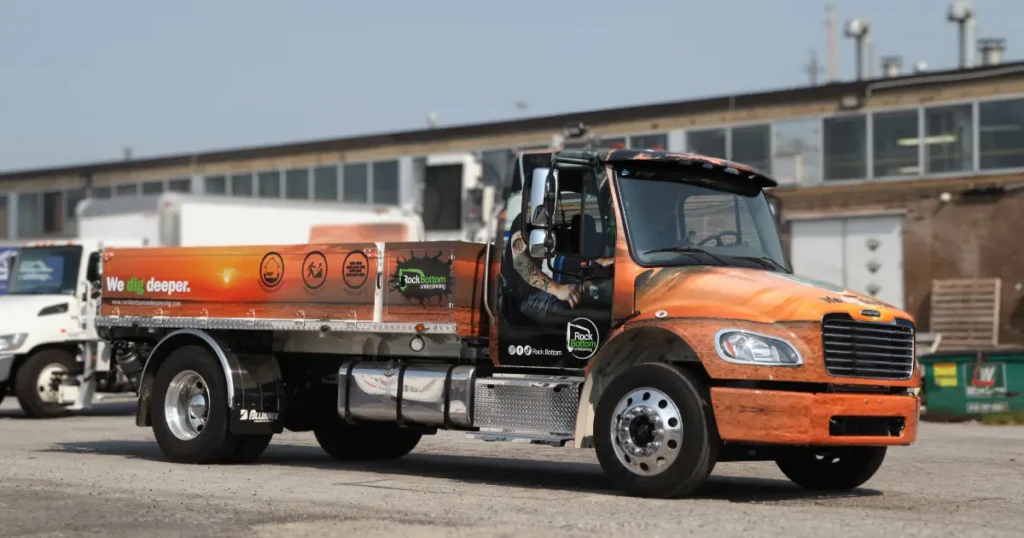 An angled side view of a Freightliner wrap displaying the Rock Bottom Underpinning company decals